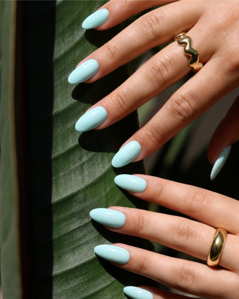 Cielo Vivo sky-blue almond press-on nails against a tropical leaf